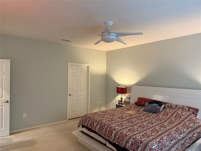 a bedroom with a large bed and a chandelier fan