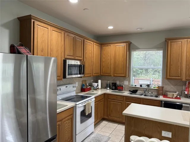 a kitchen with a refrigerator a sink a stove and cabinets