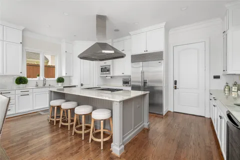 a kitchen with stainless steel appliances a dining table chairs stove and sink