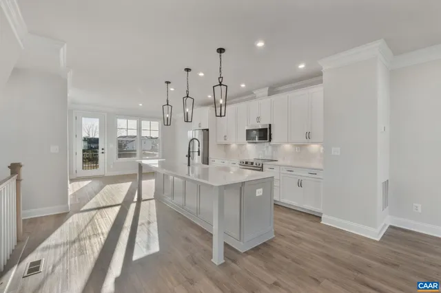 a large white kitchen with granite countertop a stove top oven a sink a counter space and stainless steel appliances