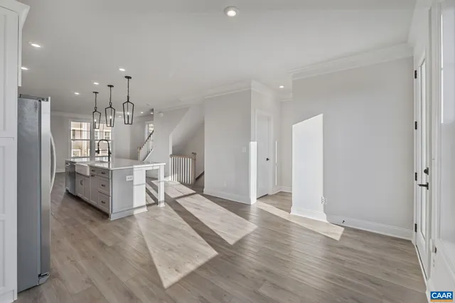 a living room with couches and kitchen view with wooden floor