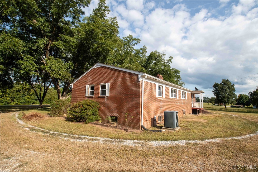View of side of home with a lawn and central AC