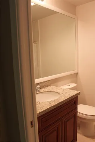 a bathroom with a granite countertop sink and a toilet