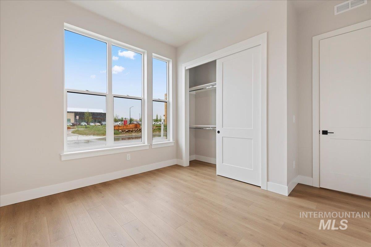 1297 West Malbar Street Meridian, ID 83646 - Photo 16 of 34 Bright room featuring wood-finish flooring, a multi-panel window, white baseboards, and a closet with sliding panel doors