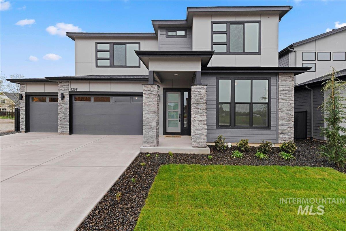 1297 West Malbar Street Meridian, ID 83646 - Photo 2 of 34 Modern architectural exterior featuring a two-car garage with frosted window panels, stone veneer accents, multi-pane windows with dark frames, and a glass-paneled entry door