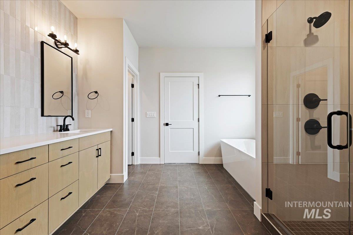 1297 West Malbar Street Meridian, ID 83646 - Photo 21 of 34 Contemporary bathroom featuring a light wood-finish vanity with matte black hardware, a frameless glass shower enclosure, a freestanding soaking tub, and vertical tile accent wall