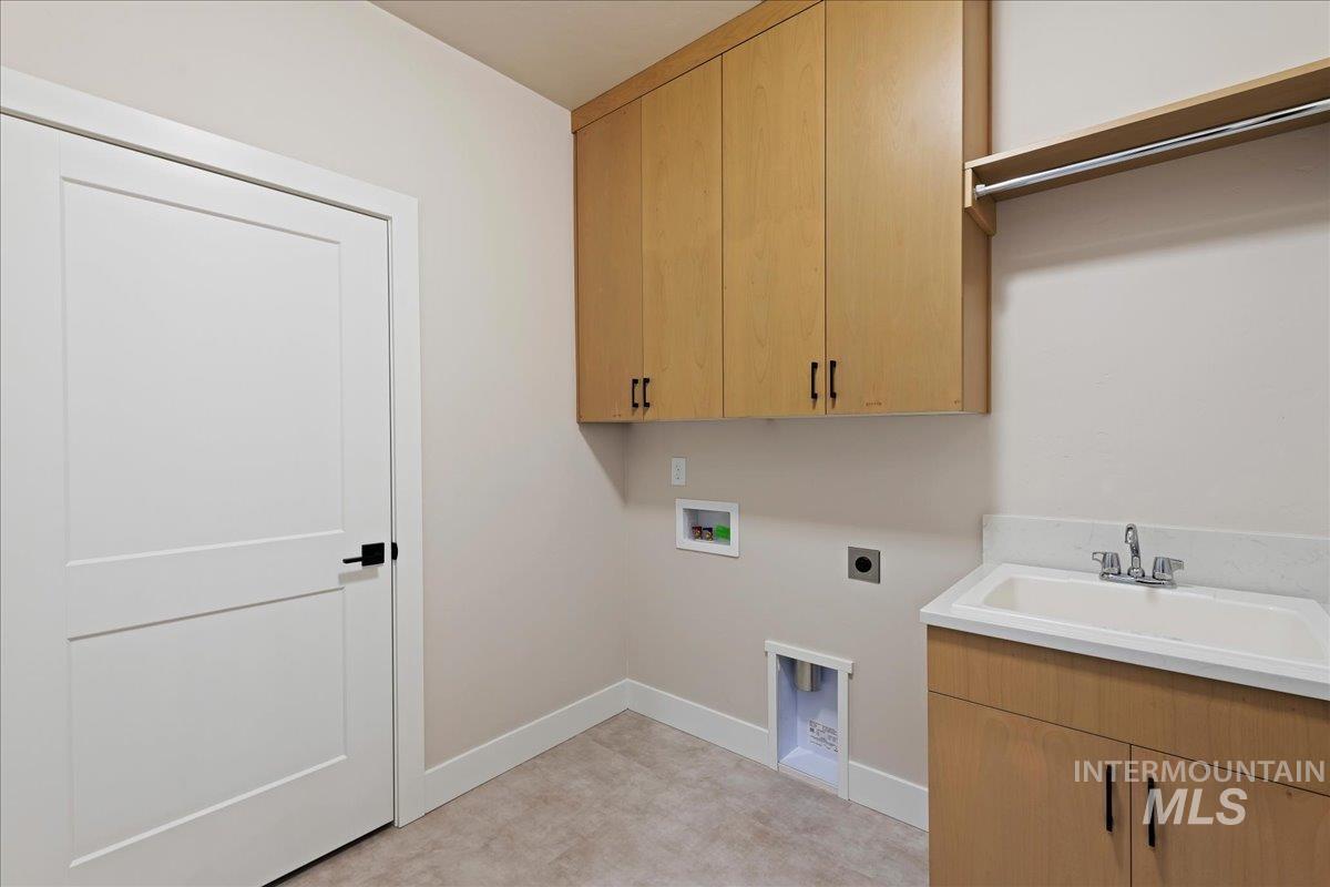 1297 West Malbar Street Meridian, ID 83646 - Photo 32 of 34 Laundry room featuring wood-finish cabinetry, a utility sink with a laminate countertop, and tile flooring