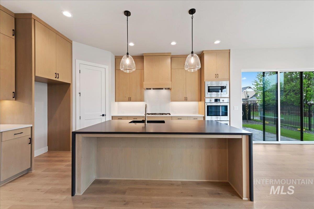 1297 West Malbar Street Meridian, ID 83646 - Photo 6 of 34 Modern kitchen featuring light wood-finish cabinetry, stainless steel appliances, a large center island with a dark countertop, and wood-finish flooring
