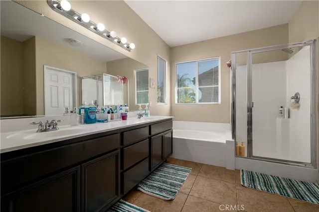 a bathroom with a double vanity sink a large mirror and a bathtub