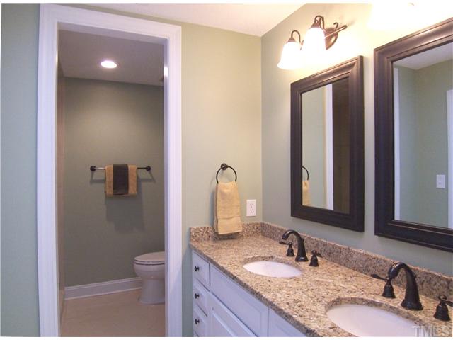6905 Brook Ridge Court Raleigh, NC 27615 - Photo 18 of 25 Master Bath has been beautifully redone: long vanity w/dbl sinks/mirrors/light fixtures, granite ctr, towel shelving tower, tile flr, lg tiled shower w/frameless glass door and lg closet.