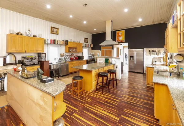 a kitchen with stainless steel appliances granite countertop a stove and a view of living room