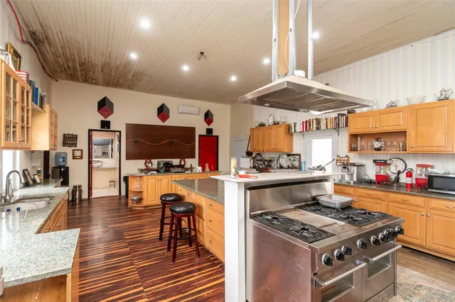 a kitchen with stainless steel appliances granite countertop a stove and a view of living room
