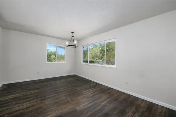 a view of an empty room with wooden floor and a fireplace