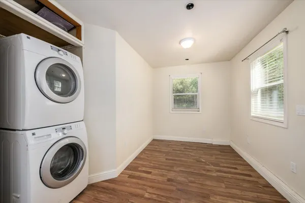 a view of an empty room with a window and wooden floor