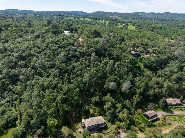 an aerial view of residential houses with outdoor space and trees