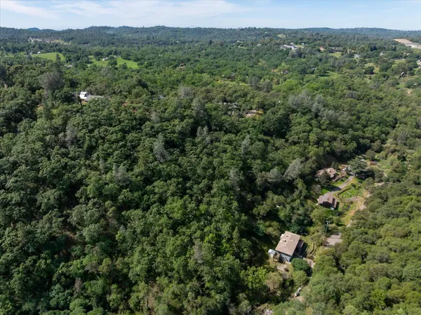 an aerial view of residential houses with outdoor space and trees