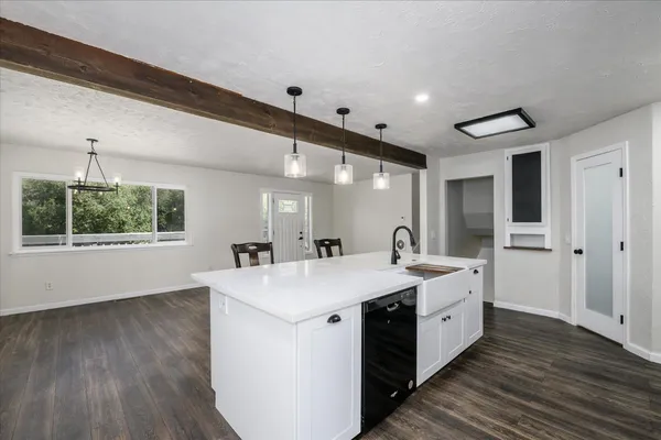 a kitchen with granite countertop a stove a sink and white cabinets with wooden floor next to windows