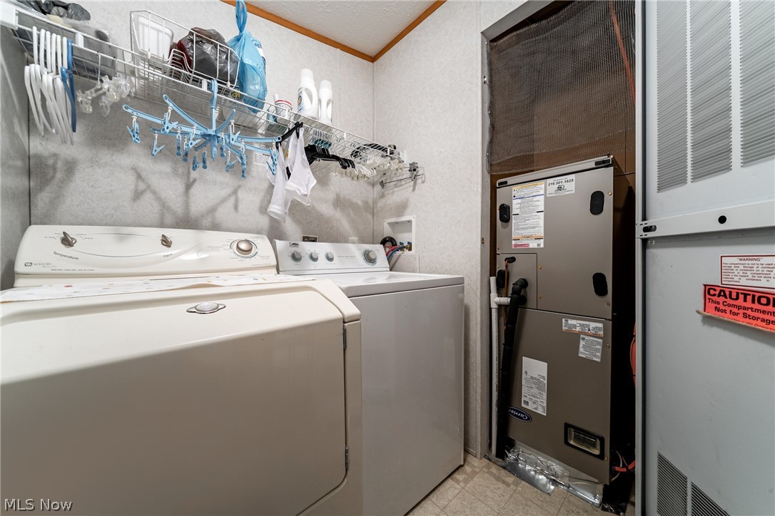 2700 Brookpark Road, Unit 513 Cleveland, OH 44134 - Photo 23 of 25 Laundry room featuring washer and dryer, a heating unit, crown molding, heating unit, and light floors