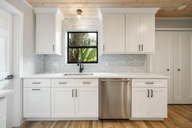 a kitchen with white cabinets and sink