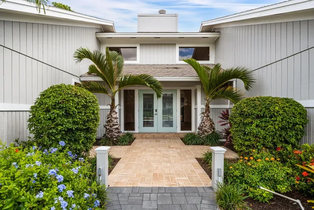 a view of a white house with a large window and flower plants