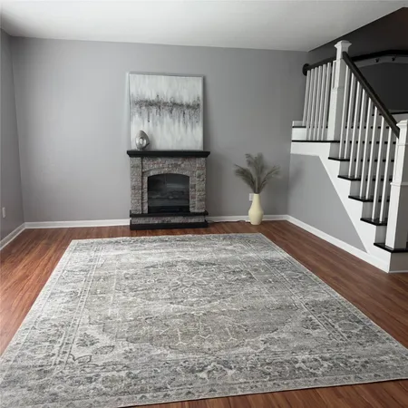 a view of an empty room with wooden floor and a fireplace