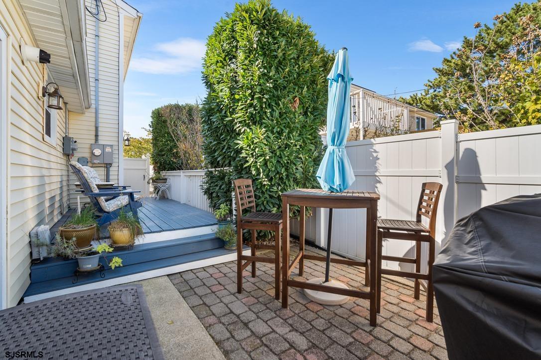 17 Manitoba Avenue Brigantine, NJ 08203 - Photo 30 of 49 a view of a patio with table and chairs and potted plants with wooden floor and fence