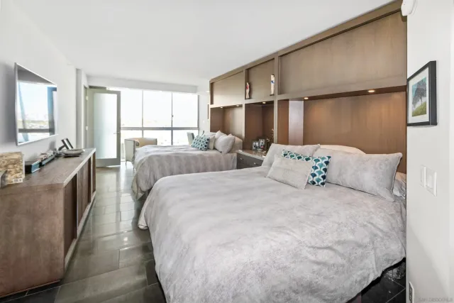 a large bed sitting in a bedroom next to a window with lamp and a dresser