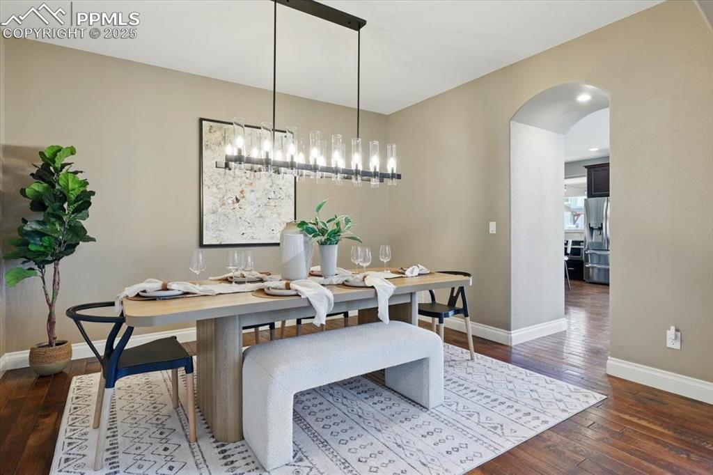 4577 Outlook Ridge Trail Colorado Springs, CO 80924 - Photo 11 of 45 a dining room with wooden floor a chandelier a wooden table and chairs