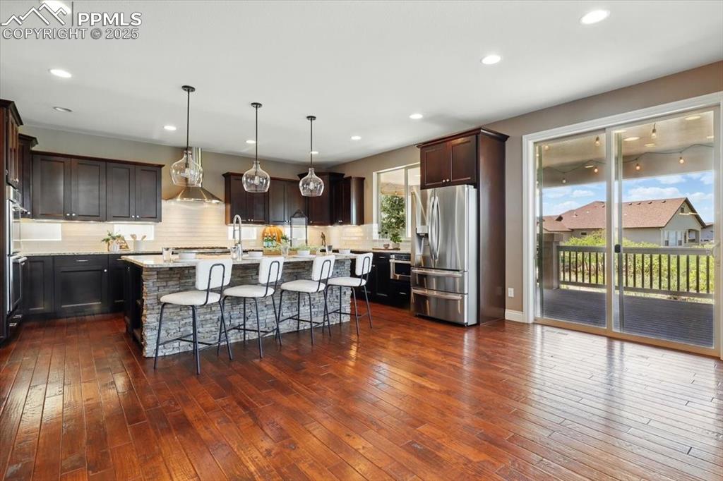 4577 Outlook Ridge Trail Colorado Springs, CO 80924 - Photo 6 of 45 an open kitchen with granite countertop a stove and a wooden floor