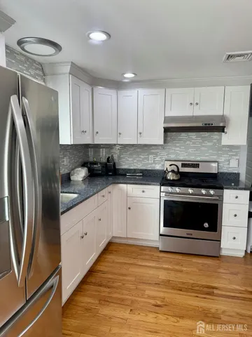 a kitchen with granite countertop white cabinets and stainless steel appliances
