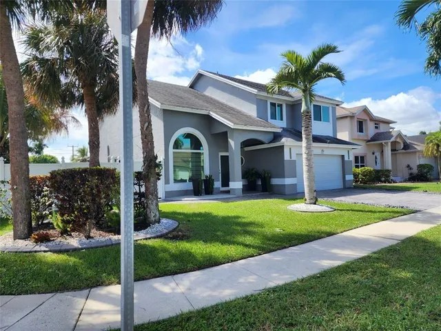 a front view of a house with a garden and palm trees
