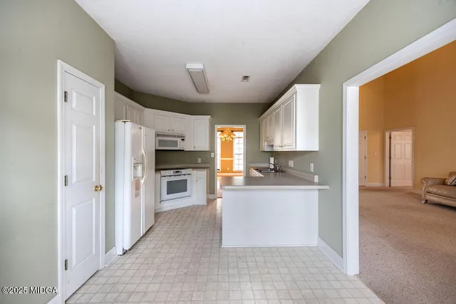 a large kitchen with a large counter top space a sink stainless steel appliances and cabinets