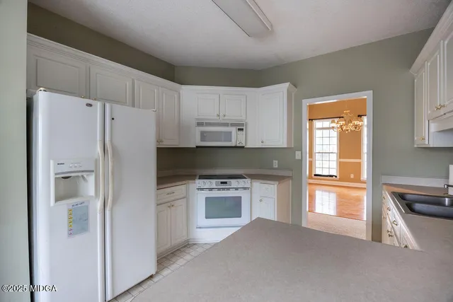a kitchen with white cabinets and refrigerator