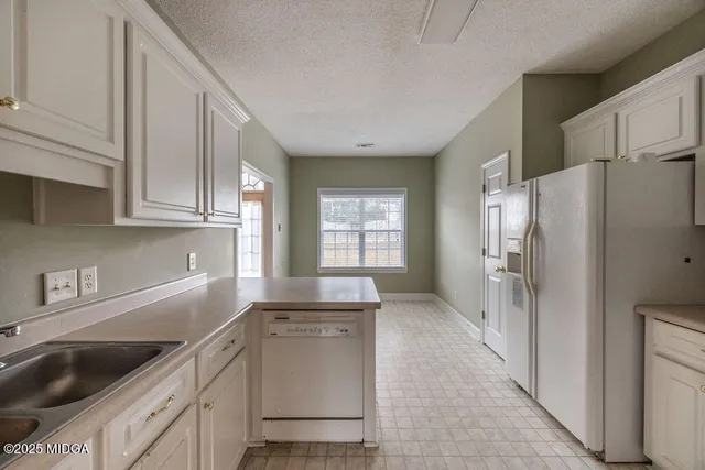 a kitchen with a refrigerator sink and cabinets
