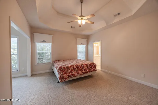 a spacious bedroom with a large bed chandelier and a window