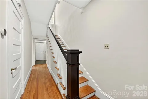 a view of a hallway with wooden floor and staircase