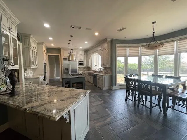 a kitchen with kitchen island granite countertop a table chairs sink and stove