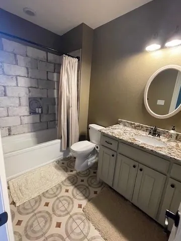 a bathroom with a granite countertop sink toilet mirror and bathtub