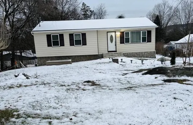 a front view of a house with a yard covered with snow