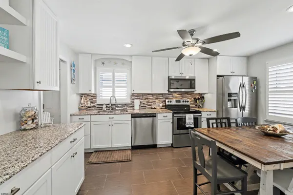 a kitchen with a dining table chairs a sink dishwasher a stove and a dining table with wooden floor