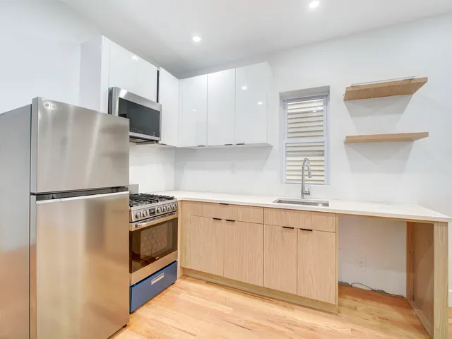 a kitchen with stainless steel appliances a refrigerator a sink and white cabinets