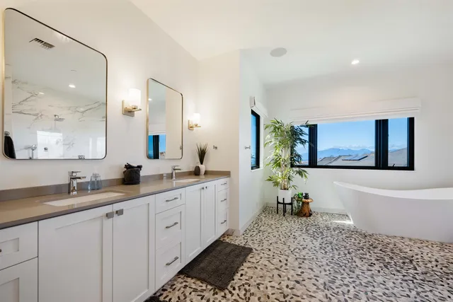 a spacious bathroom with a double vanity sink a mirror and a bathtub