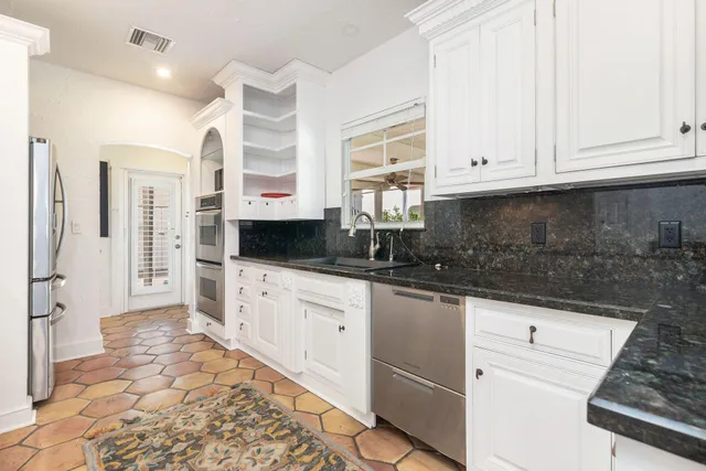 a kitchen with granite countertop a sink a stove and cabinets