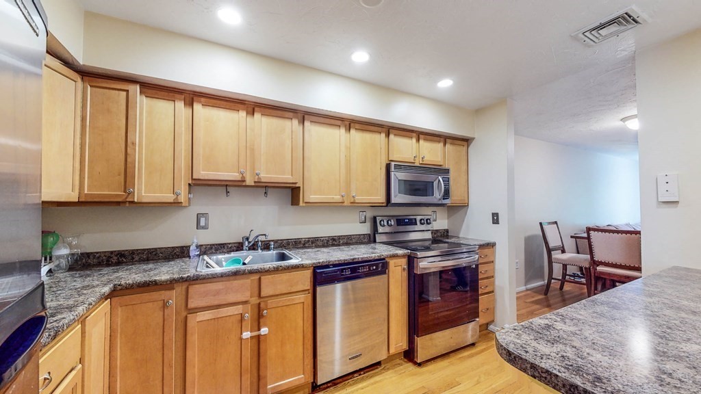 a kitchen with stainless steel appliances granite countertop sink stove top oven and cabinets