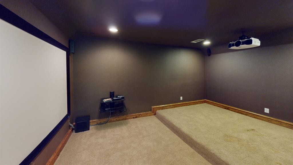 4516 Gilbert Avenue Dallas, TX 75219 - Photo 15 of 28 Dedicated media room featuring a large projection screen, mounted projector, recessed lighting, and a tiered carpeted floor