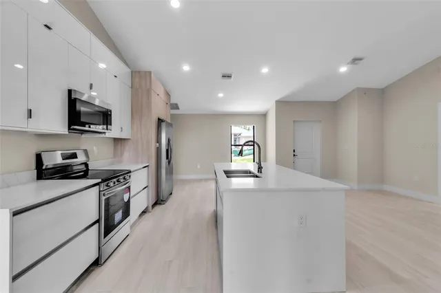 a kitchen with stainless steel appliances kitchen island granite countertop a sink and a stove top oven with wooden floor