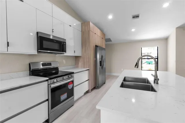 a kitchen with granite countertop a sink a stove and stainless steel appliances