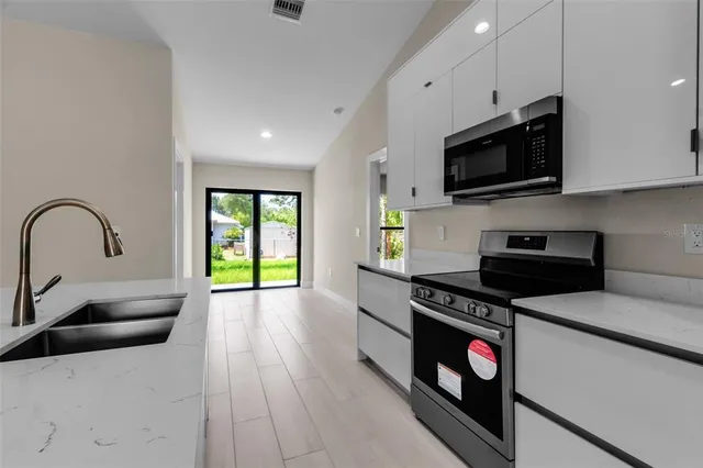 a kitchen with granite countertop a stove a sink and a microwave