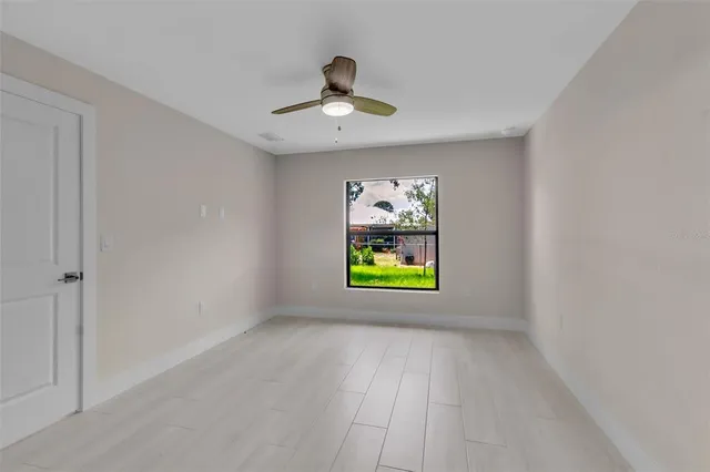 an empty room with window and ceiling fan