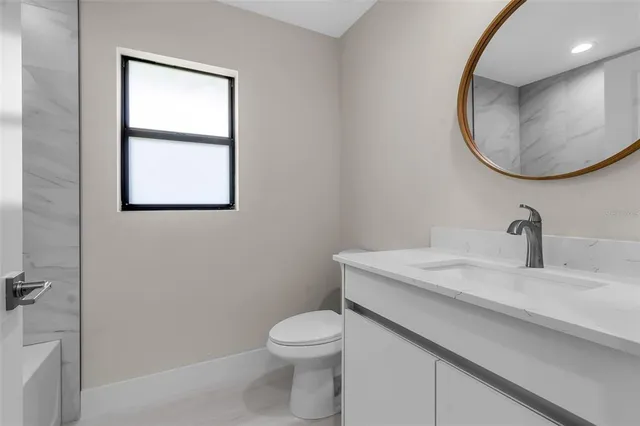 a bathroom with a granite countertop toilet sink and mirror